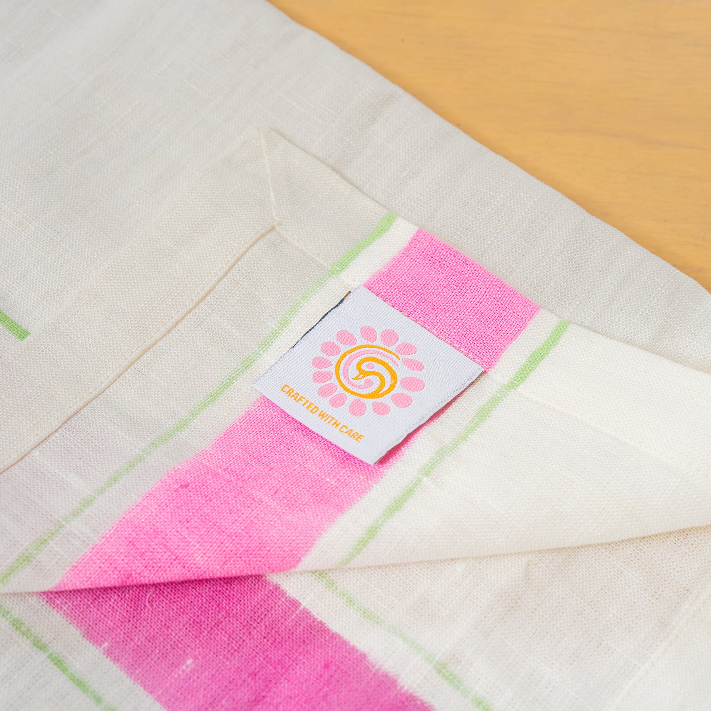Hand printed linen napkins in pink, folded with the peacock palette label laid out on a table