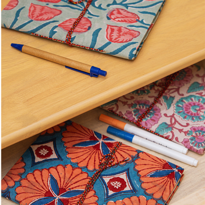 Colorful hand block printed journals with markers on a wooden surface