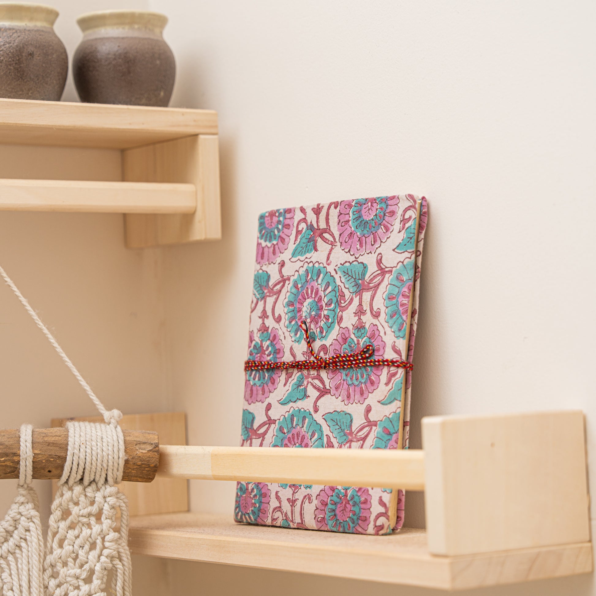 Hand printed cotton cover journal  in teal floral pattern on  wooden shelf