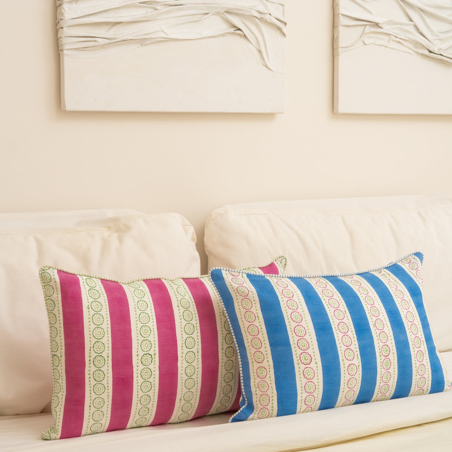 Two striped pillows on a beige sofa with a neutral wall in the background