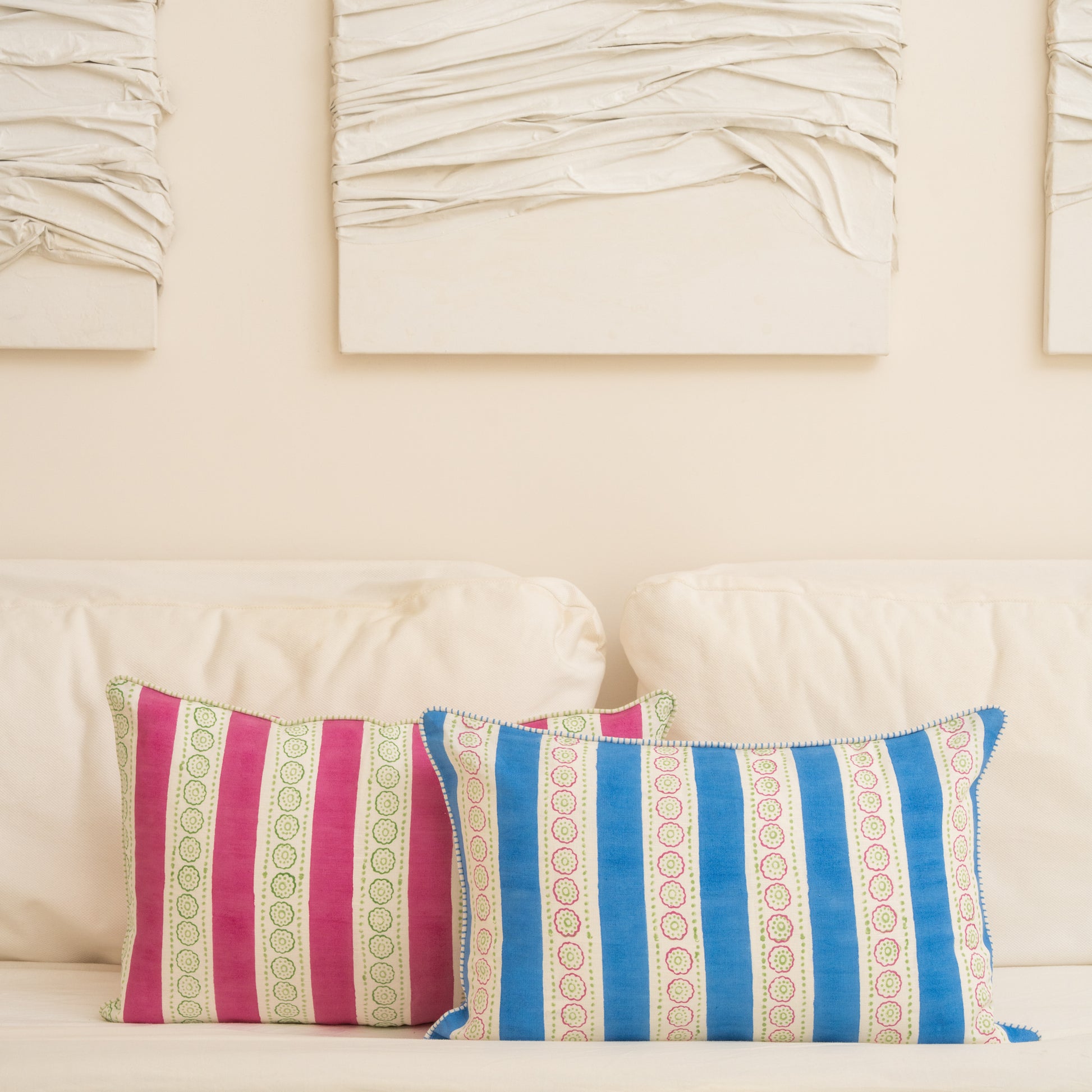 Two decorative pillows with striped patterns on a beige sofa.