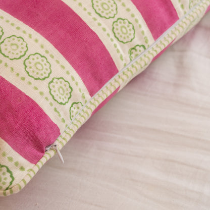 Close-up of Hand block printed linen pillow cover with pink stripes and floral motifs in natural dyes placed on  a beige background