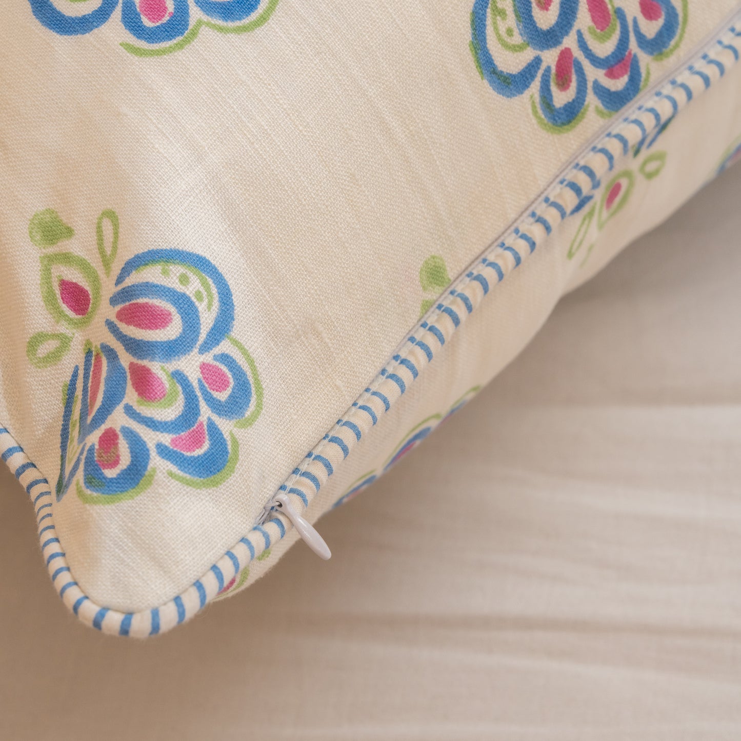 Peacock blue hand block printed linen pillow cover with intricate feather motif in natural dyes. Close-up of a fabric  on a beige background