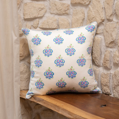 Peacock blue hand block printed linen pillow cover with intricate feather motif in natural dyes, styled on a stone wall background