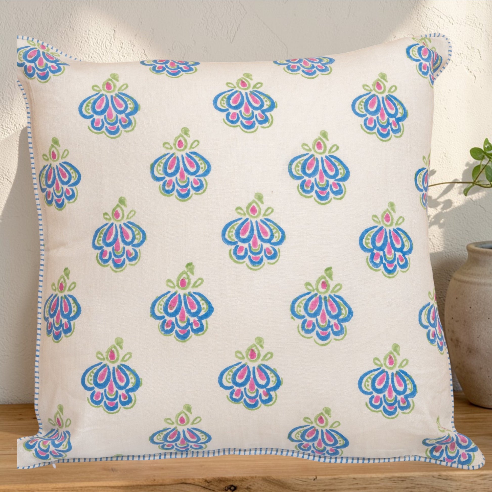 Decorative hand block printed linen pillow with colorful pattern in natural dyes placed on a wooden surface
