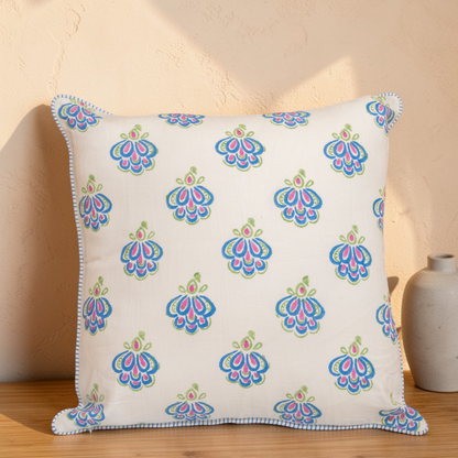 Peacock blue hand block printed linen pillow cover with intricate feather motif in natural dyes, placed on a wooden surface