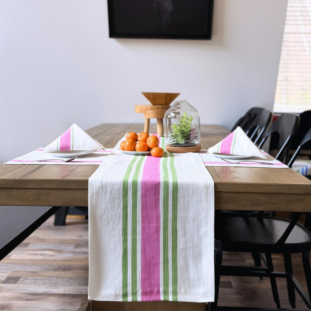 Dining table with pink and green striped hand block printed linen runner, oranges, and decorative items in a room.