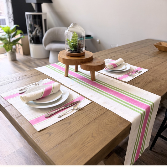 Dining table set with pink and green striped hand block printed linen table runner, plates, and cutlery in a modern living room.