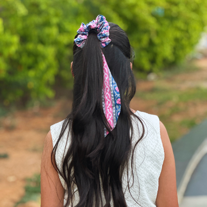 Person with long hair wearing a colorful scrunchie and headband outdoors