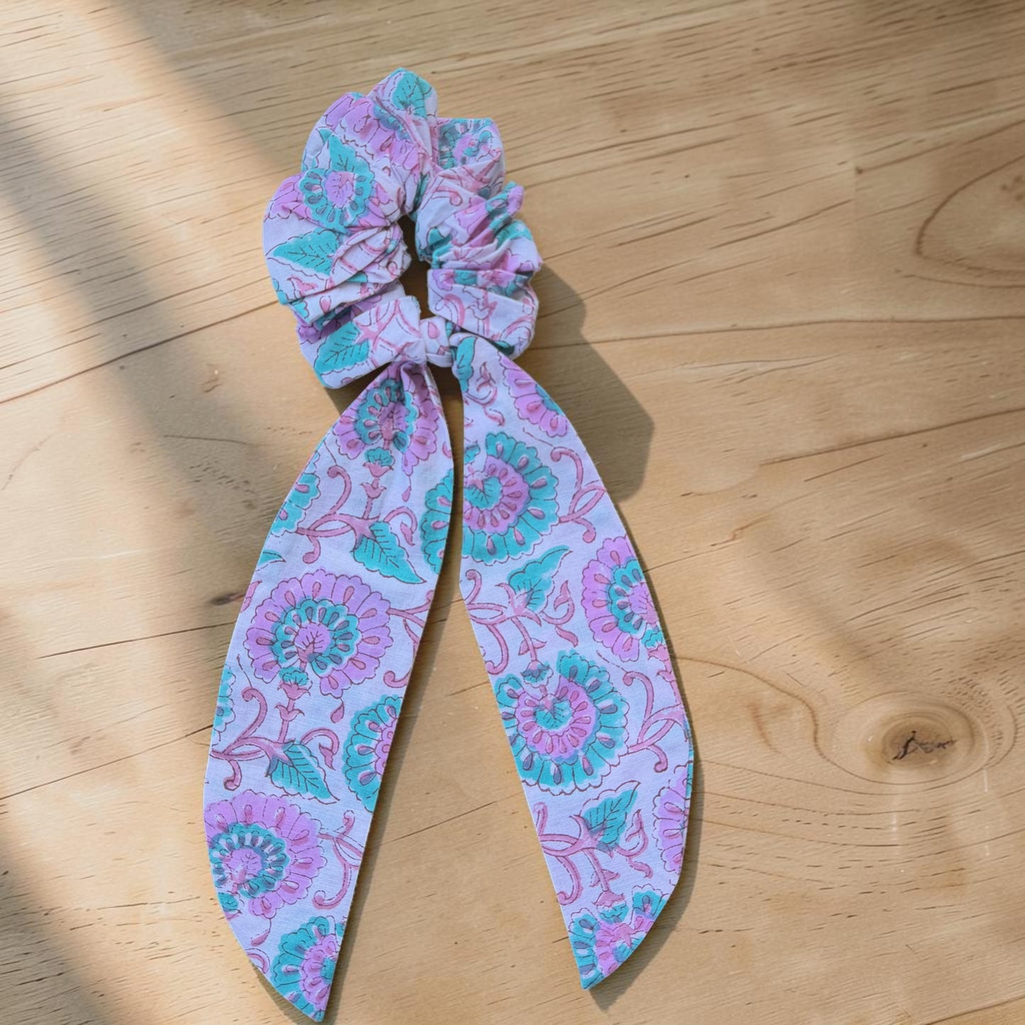 Hand Block Printed Cotton Patterned scrunchie with a long tail on a wooden surface
