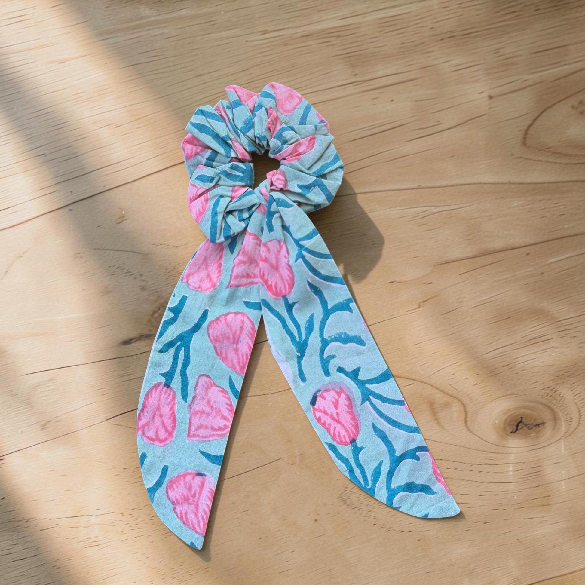 Hand printed cotton scrunchies in pink patterns laid out on wooden surface