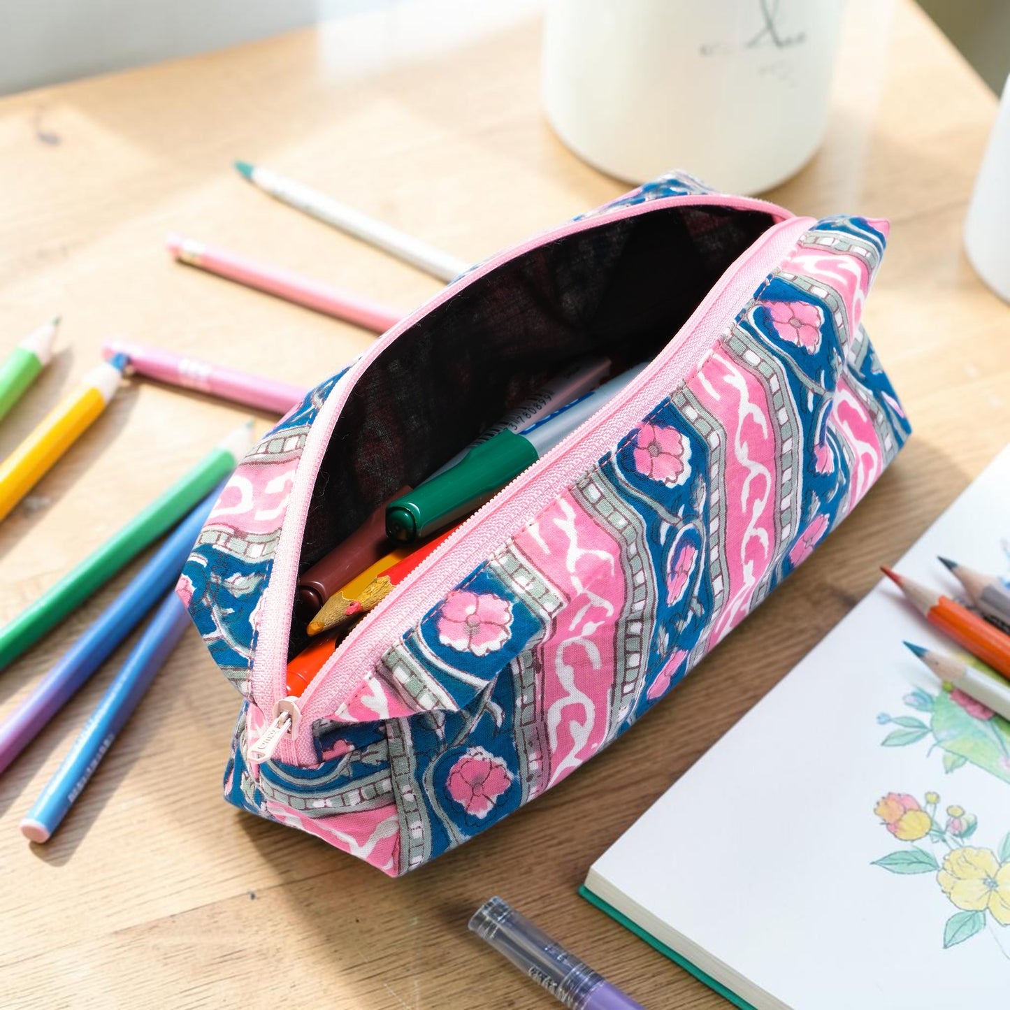 Cotton Hand Block Printed Pink and blue patterned pencil case with pens on a wooden table